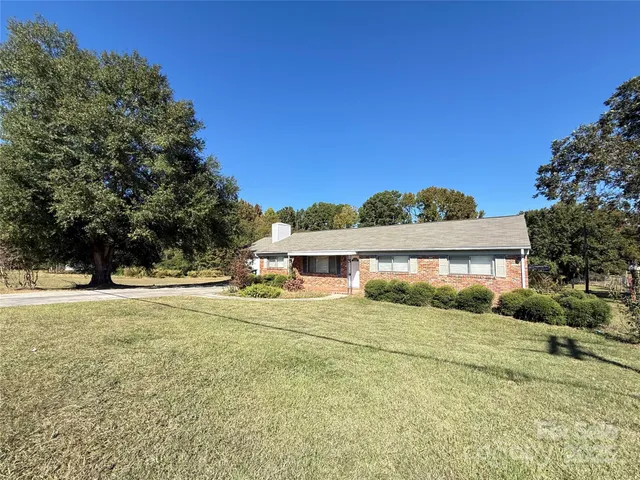 a view of a house with a yard and large trees
