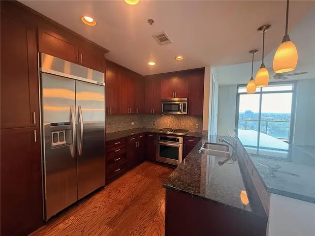 a kitchen with granite countertop stainless steel appliances a stove a sink and a microwave