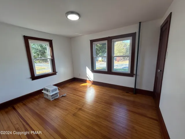 a view of an empty room with window and wooden floor