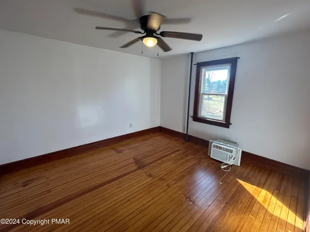 a view of an empty room with window and wooden floor