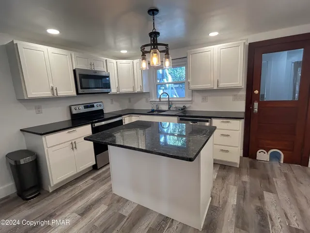 a kitchen with stainless steel appliances granite countertop a sink a stove and a microwave