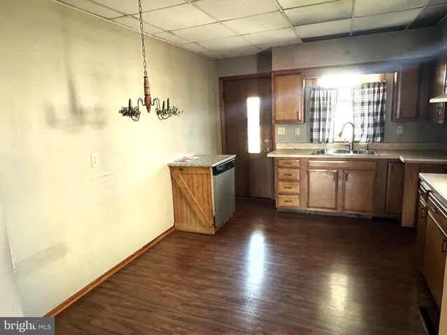 a large kitchen with kitchen island a sink dishwasher a stove and a dining table with wooden floor