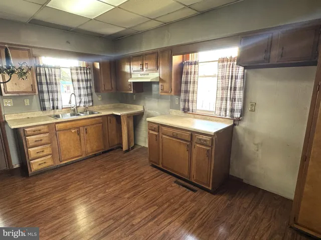 a kitchen with stainless steel appliances granite countertop a sink a stove a refrigerator with wooden cabinets and wooden floor