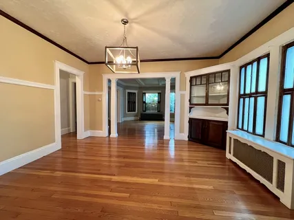 a view of a hall with wooden floor and chandelier