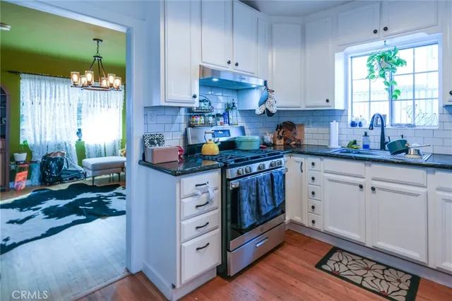an empty room with wooden floor cabinet and windows
