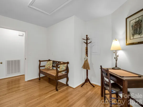 a view of a hallway with wooden floor and a bathroom