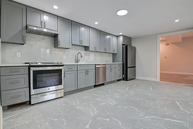 a kitchen with white cabinets stainless steel appliances and a refrigerator