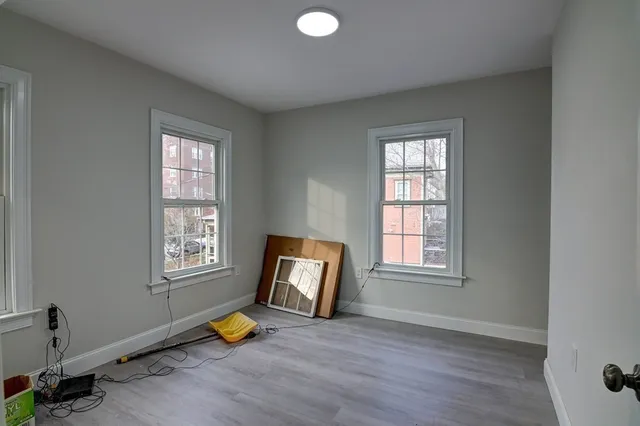 an empty room with wooden floor and windows