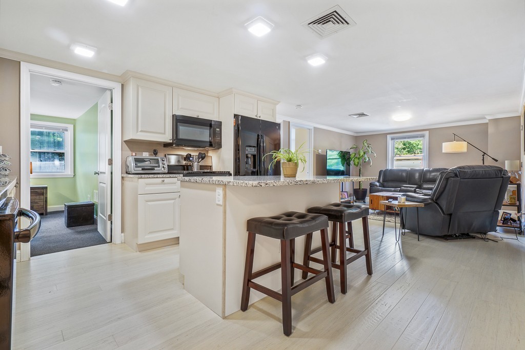 10 Riverbank Road, Unit 3 Maynard, MA 01754 - Photo 6 of 20 a living room with furniture a flat screen tv and kitchen view