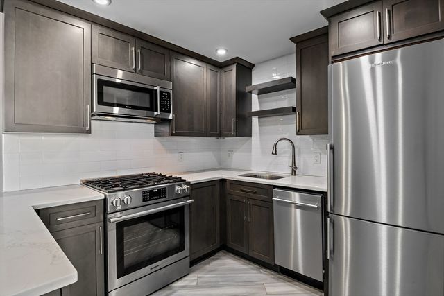 a kitchen with stainless steel appliances granite countertop a refrigerator stove a sink and dishwasher a refrigerator with wooden floor