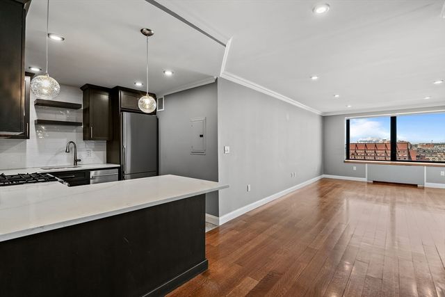 a large kitchen with a large counter top a sink stainless steel appliances and cabinets