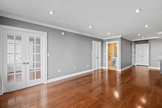 a view of an empty room with wooden floor and windows