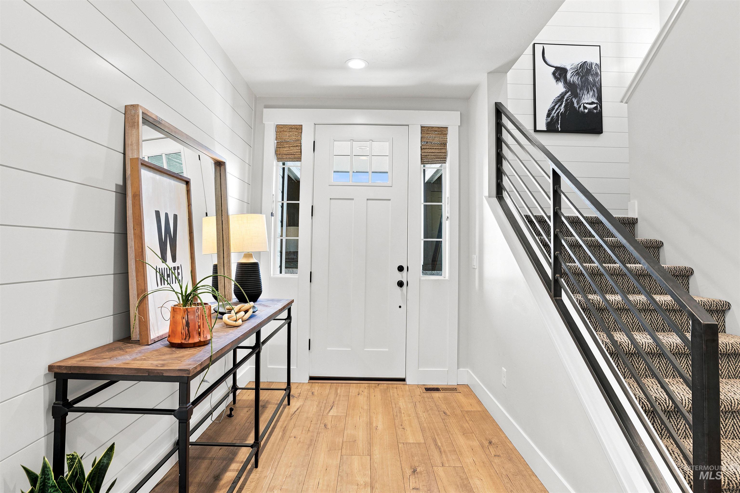 4323 West Ladle Rpds Drive Meridian, ID 83646 - Photo 5 of 49 Entryway featuring a Craftsman-style front door with frosted glass panels, wood-finish flooring, shiplap accent wall, and a staircase with a modern metal railing and carpeted treads