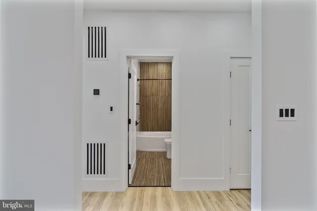 an empty room with wooden floor and a bathroom