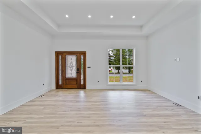 a view of an empty room with wooden floor and windows