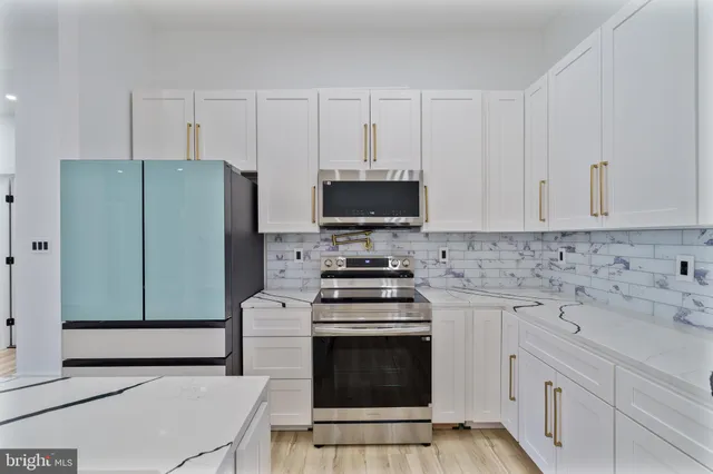 a kitchen with granite countertop white cabinets and stainless steel appliances