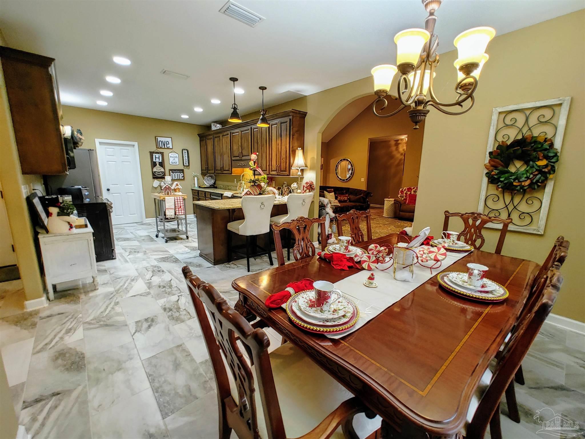 415 Clark Road Gilbertown, AL 36908 - Photo 14 of 50 a view of a dining room and livingroom with furniture wooden floor a rug a chandelier and a mirror