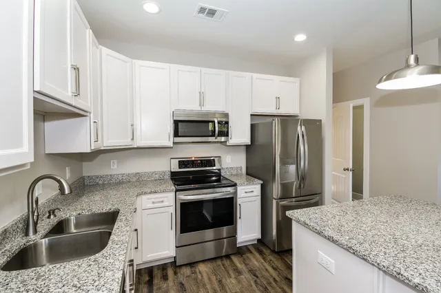 a kitchen with granite countertop a sink stainless steel appliances and white cabinets