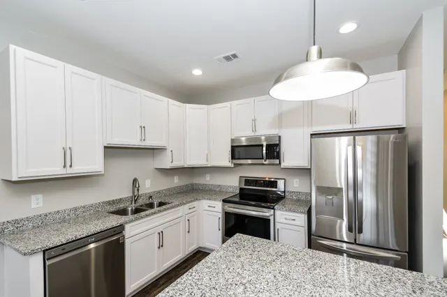 a kitchen with kitchen island granite countertop a refrigerator a sink a stove a microwave and wooden cabinets