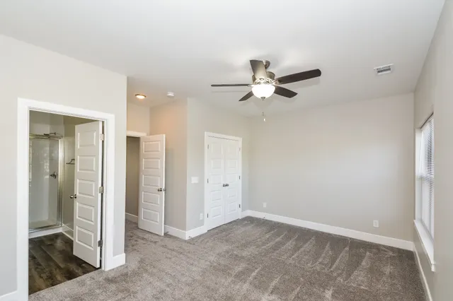 an empty room with closet and a ceiling fan