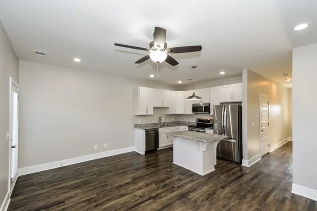 a kitchen with a center island wooden floor and stainless steel appliances