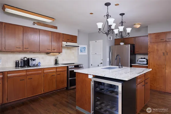 a kitchen with a stove a sink a refrigerator and a wooden floor