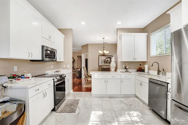 a kitchen with stainless steel appliances granite countertop a stove top oven a sink dishwasher and a refrigerator with wooden cabinets