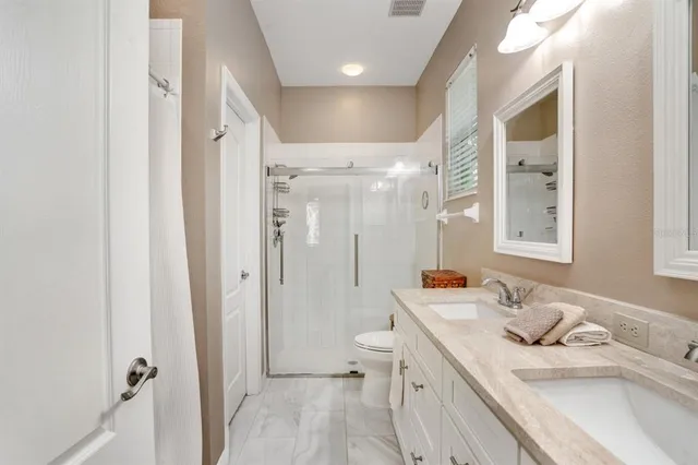 a bathroom with a sink toilet double vanity and shower