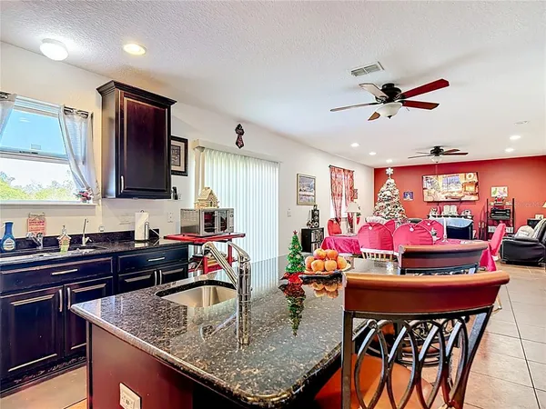 a kitchen with stainless steel appliances granite countertop a sink counter space and living room view