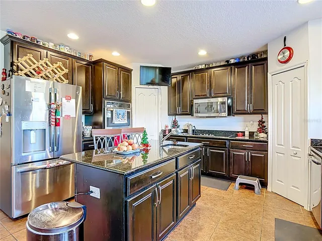 a kitchen with stainless steel appliances kitchen island granite countertop a stove refrigerator and cabinets