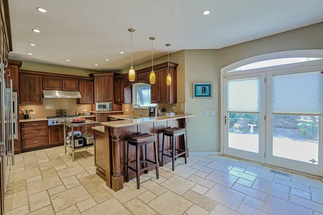 a open dining hall with stainless steel appliances granite countertop a stove a sink a dining table and chairs