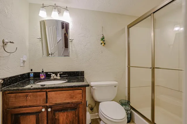 a bathroom with a granite countertop sink mirror vanity and toilet