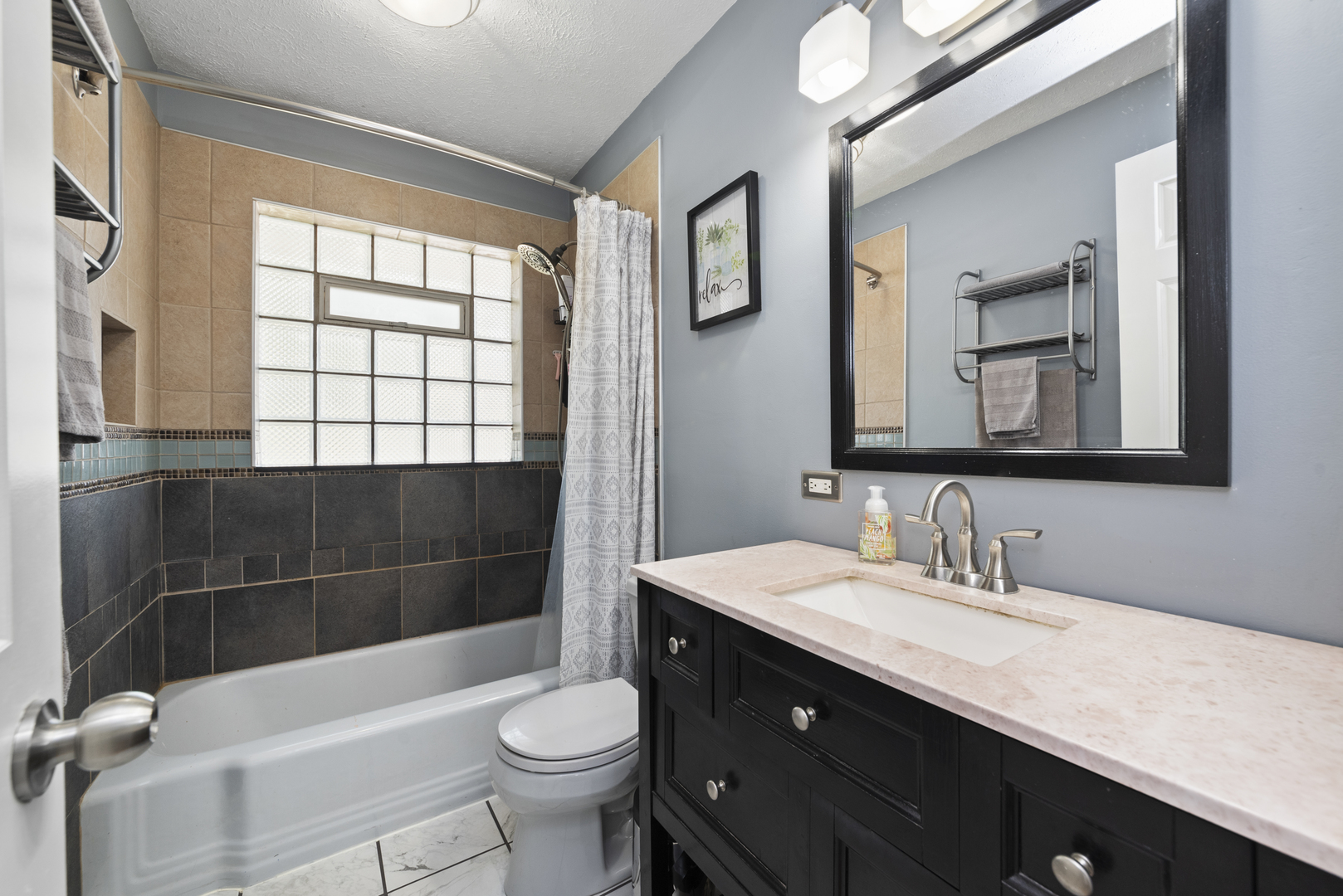 943 Sumner Street Addison, IL 60101 - Photo 10 of 20 a bathroom with a sink a toilet a mirror and bathtub