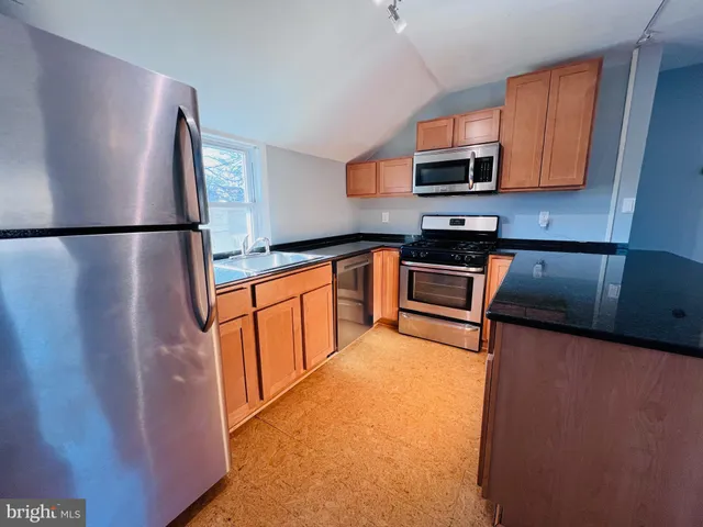 a kitchen with stainless steel appliances granite countertop a refrigerator a stove a sink a microwave a counter top and oven