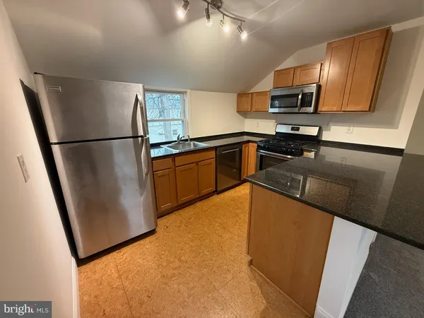 a kitchen with granite countertop a refrigerator a stove top oven a sink and dishwasher