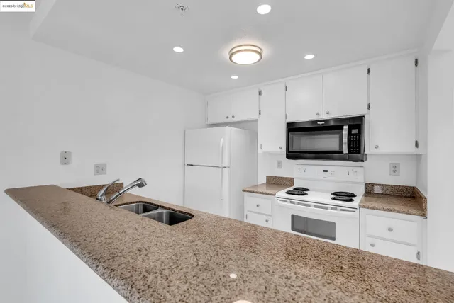 a kitchen with granite countertop white cabinets and stainless steel appliances