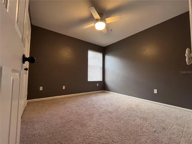 an empty room with windows and fan