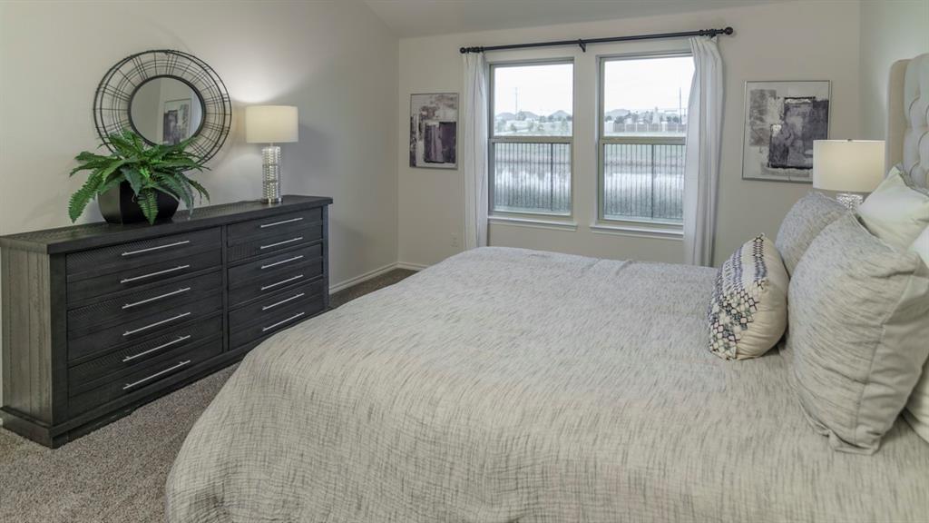 3100 Charleston Drive Ennis, TX 75119 - Photo 4 of 23 Carpeted bedroom featuring multiple windows with white curtains, a tufted headboard, and light-toned walls