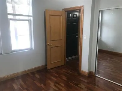 an empty room with wooden floor closet and windows