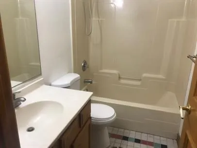 a white toilet sitting next to a bathroom sink and vanity