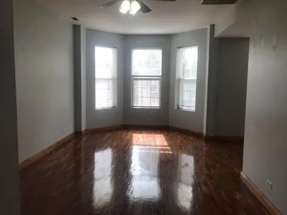 a view of empty room with wooden floor and fan