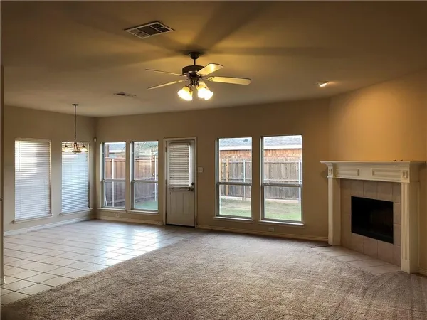 a view of an empty room with window and chandelier fan