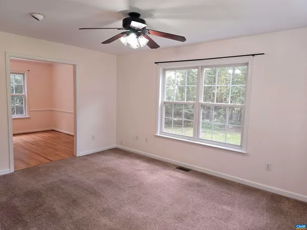 an empty room with chandelier fan and windows