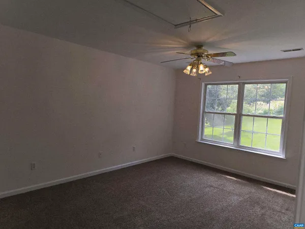 an empty room with a window and a fan