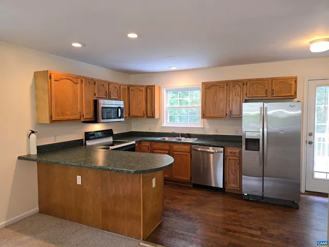 a kitchen with stainless steel appliances granite countertop a sink a stove a refrigerator cabinets and a counter top space