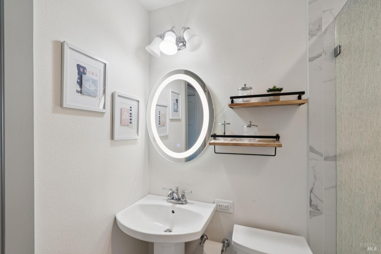 88 Cypress Loop Bodega Bay, CA 94923 - Photo 70 of 88 Dual-entry bathroom on the main level with modern tile floors, backlit mirror, pedestal sink and shower stall featuring a rain tempered glass panel and marble tile.