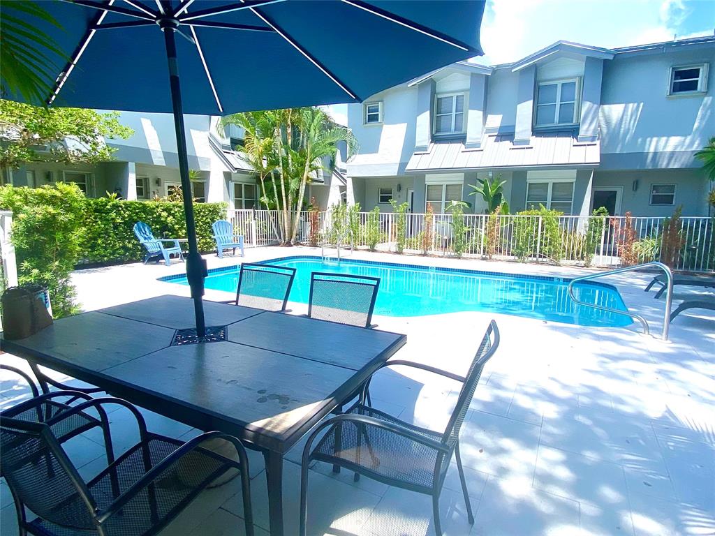 801 Southeast 16th Court, Unit 11 Fort Lauderdale, FL 33316 - Photo 46 of 49 a patio with a table and chairs under an umbrella