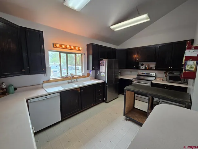 a large kitchen with stainless steel appliances a stove a sink dishwasher and a microwave oven with cabinets