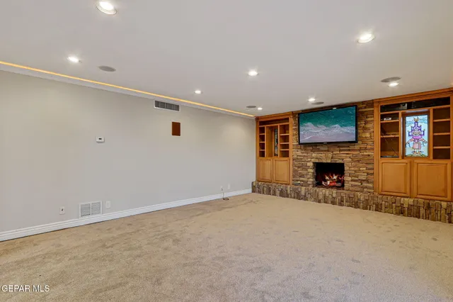 an empty room with a fireplace and cabinet