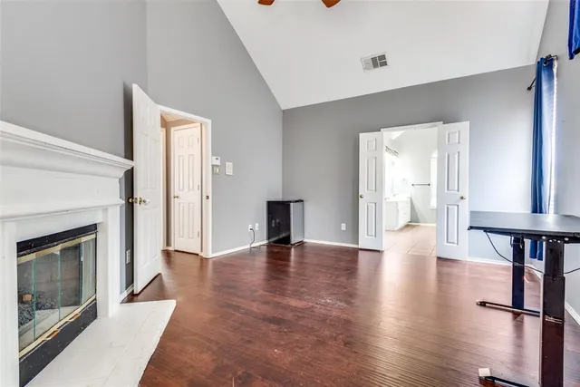 a view of an empty room with wooden floor fireplace and a window